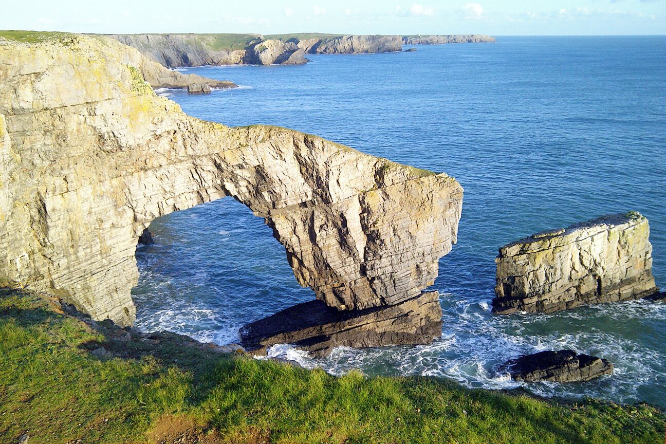 A coastal landscape with a prominent rock arch formation.