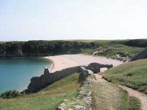 Eine Küstenlandschaft mit einem Sandstrand, einem Steinweg und einer Steinbrücke, die zum Strand führt.