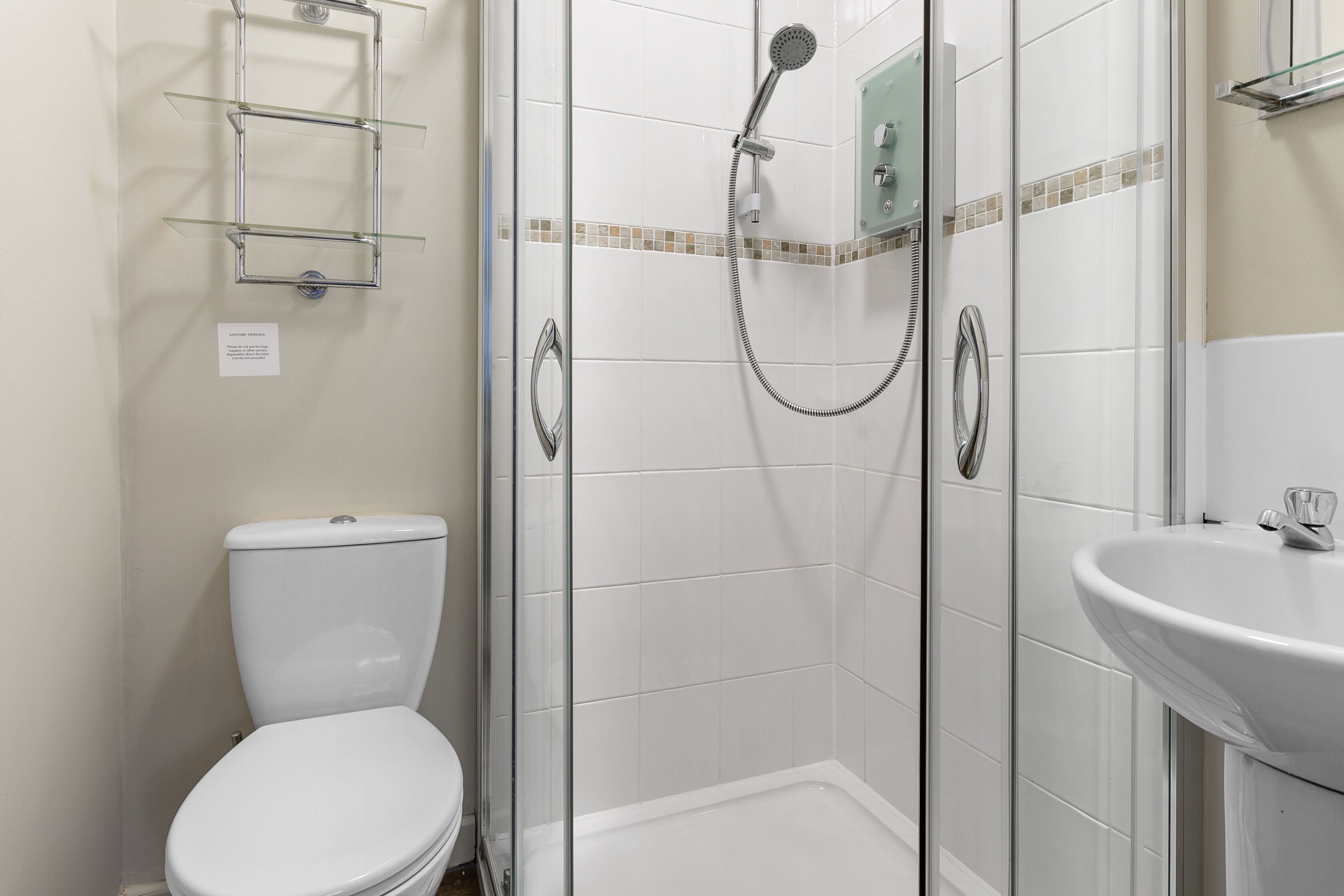 A bathroom with a toilet, a shower with a glass door, and a sink.