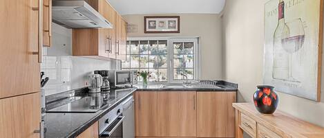 A modern kitchen with wooden cabinets, a black countertop, and a large window providing natural light.