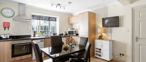 A modern kitchen with a dining table, chairs, and a TV.