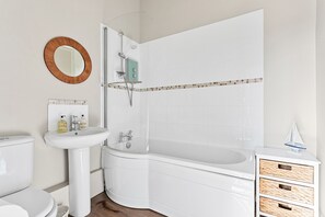 Bathroom features a pedestal sink, bathtub, and toilet.