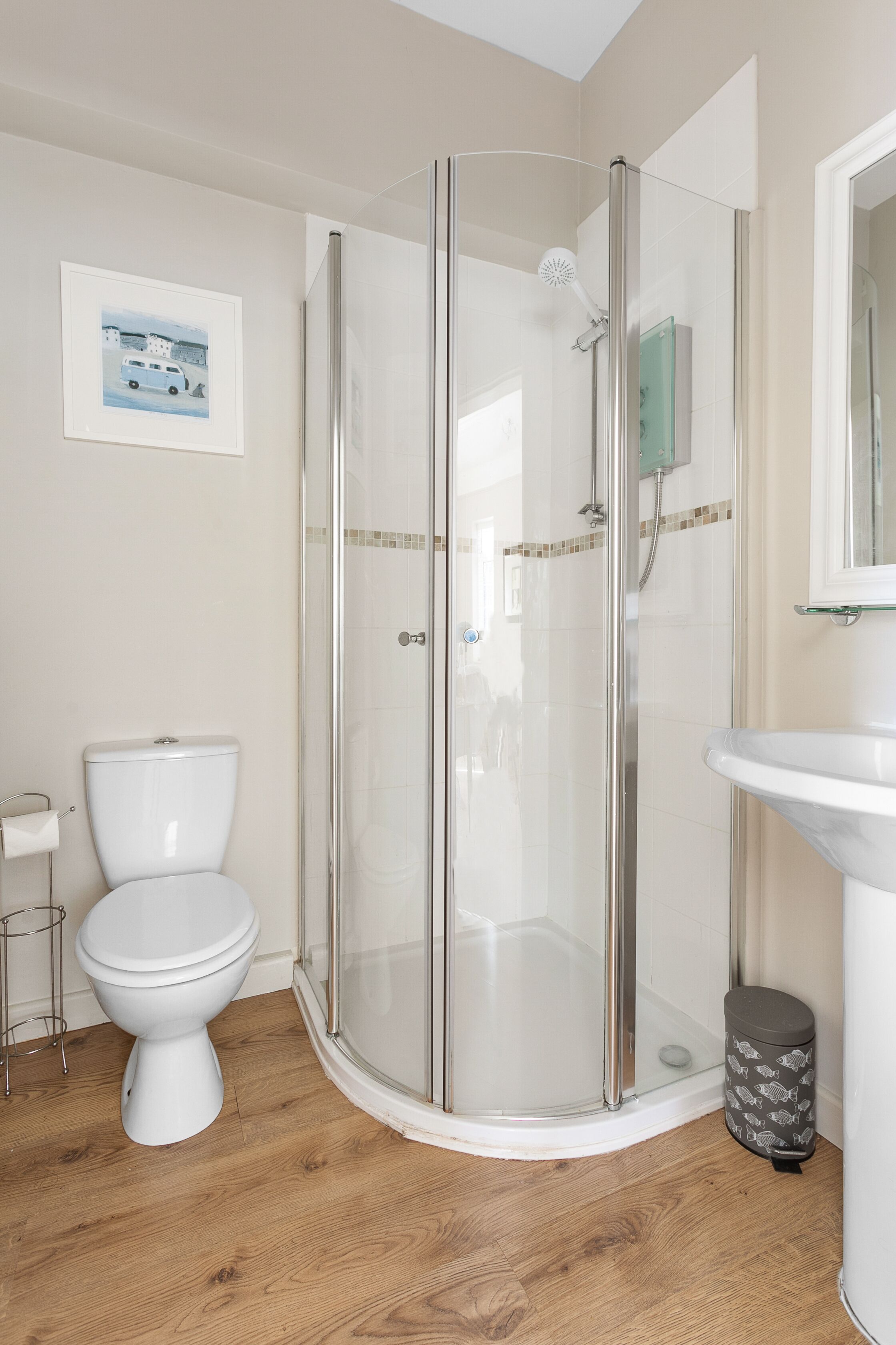 A modern bathroom with a glass-enclosed shower, a white toilet, and a sink.