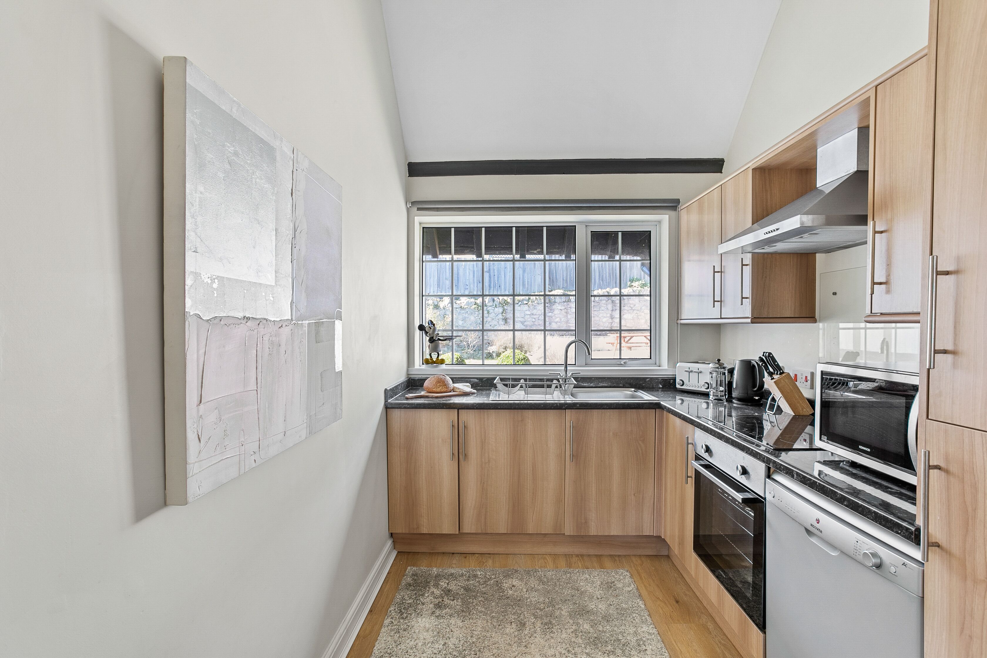 A modern kitchen with wooden cabinets, stainless steel appliances, and a large window providing natural light.