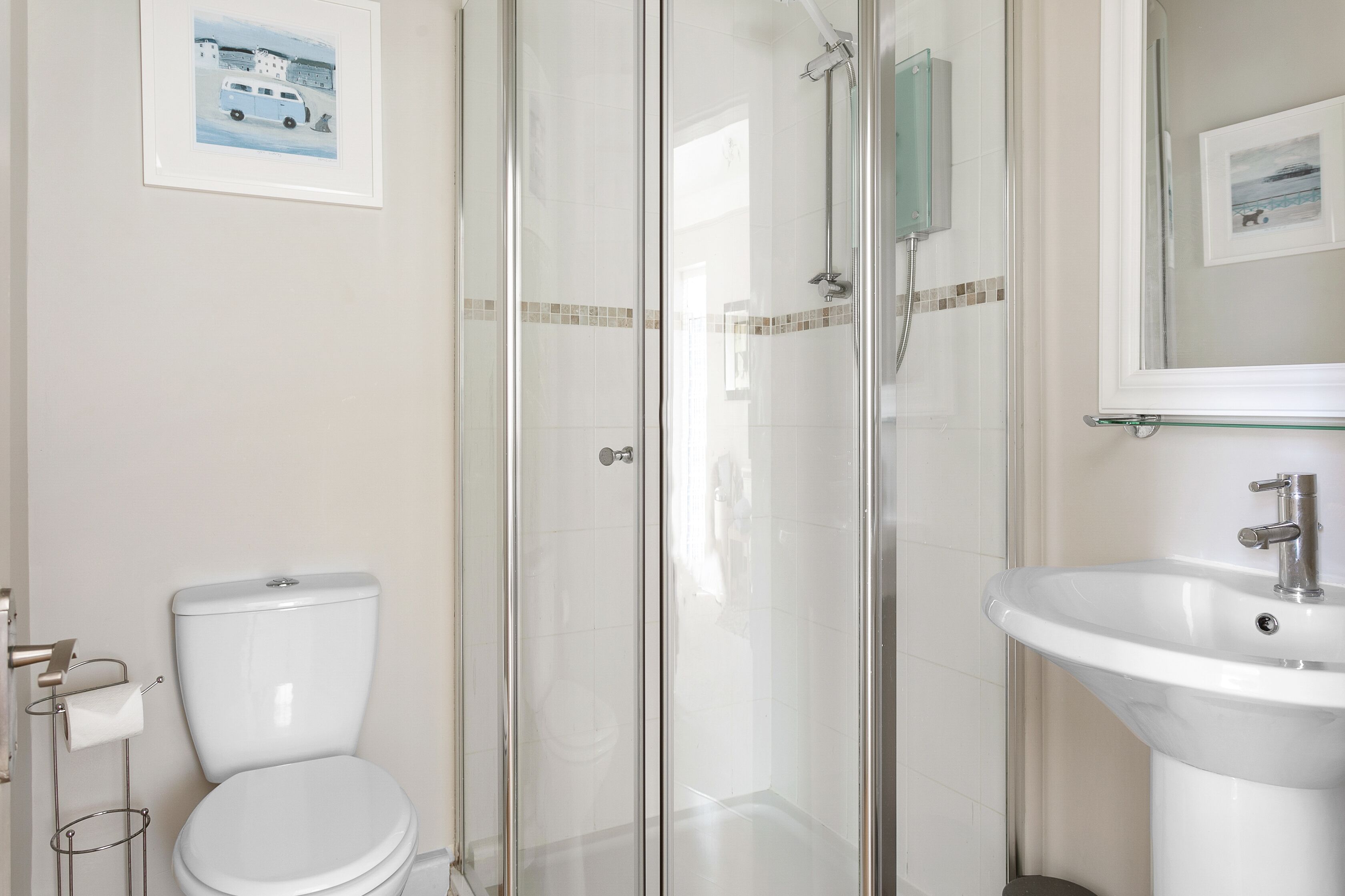 Een badkamer met toilet, een douche met glazen wand en een wastafel.
