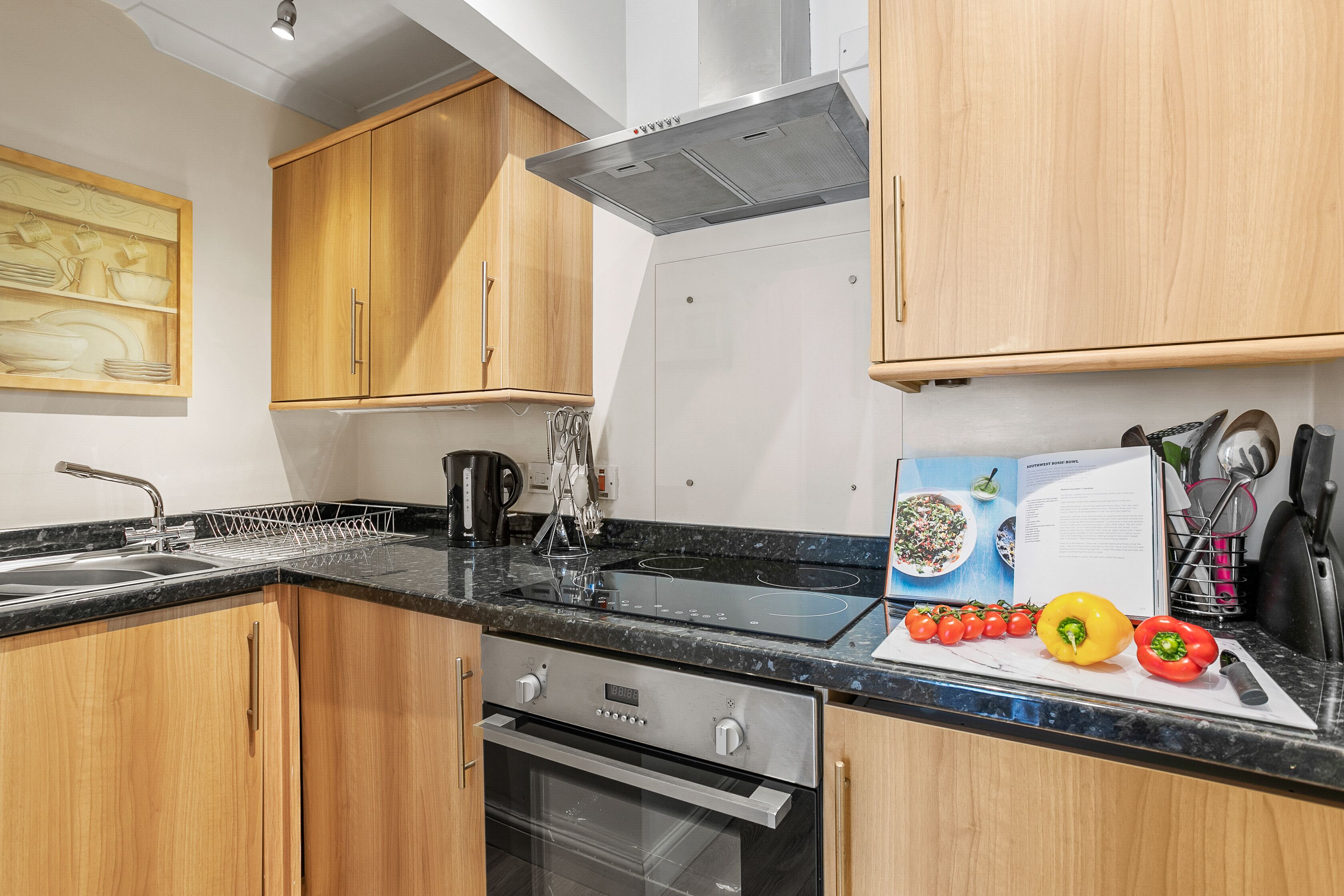 A modern kitchen with wooden cabinets, a stainless steel range hood, and a granite countertop.