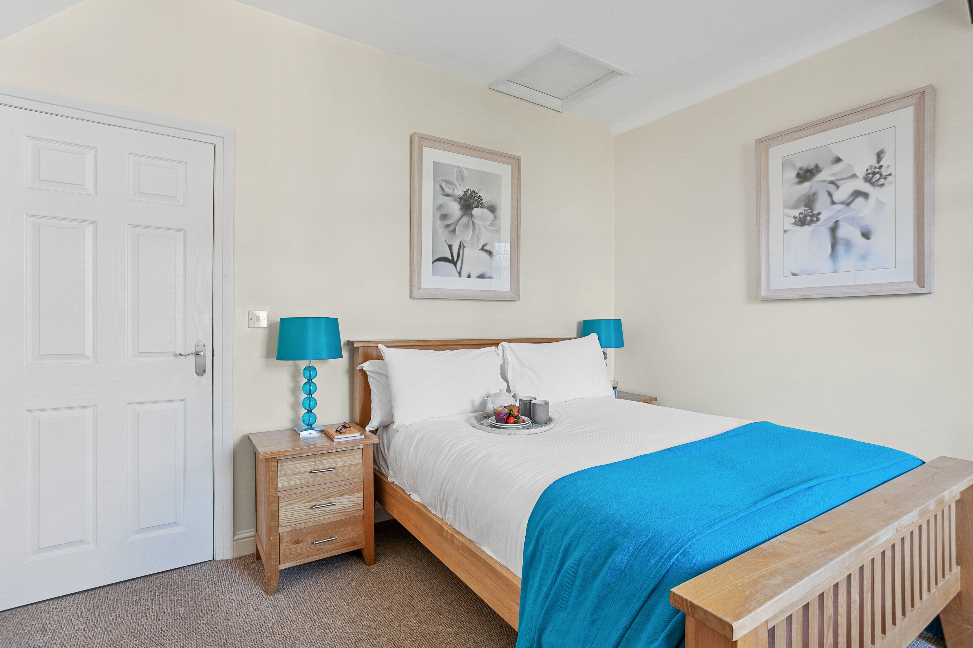 A bedroom with a bed, bedside tables, and artwork on the walls.