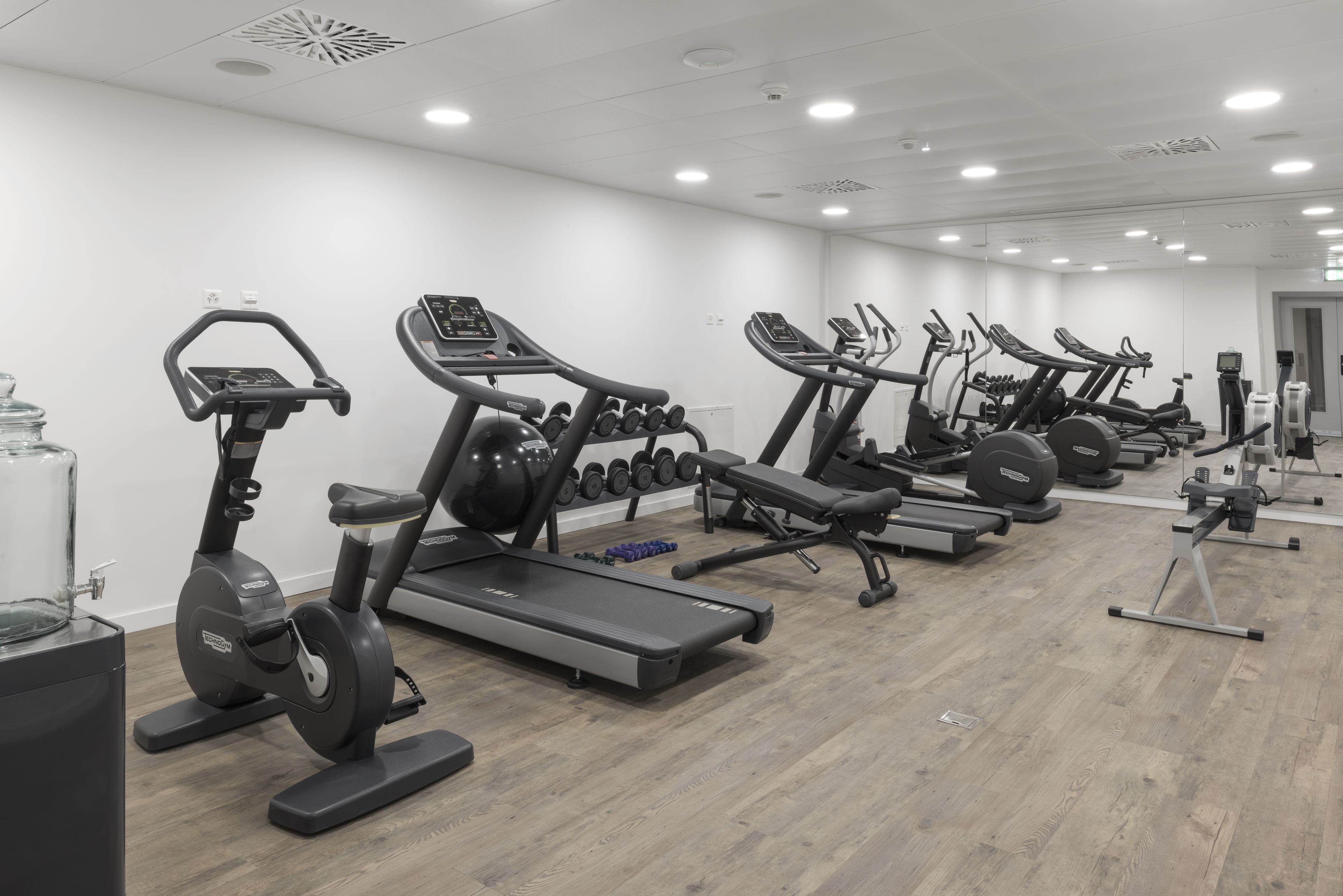 A gym with multiple treadmills, elliptical machines, and a variety of weights.