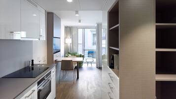 A modern kitchen with white cabinetry, a dining area with a table and chairs, and a view of the city through large windows.