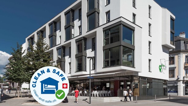 A modern building with a clean and safe logo, featuring a checkmark and a house icon.
