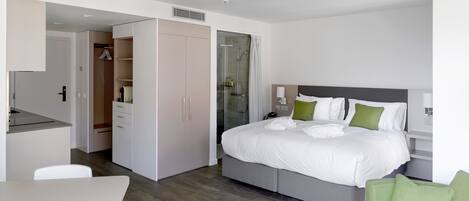 A modern hotel room with a bed, a desk, and a shower area.