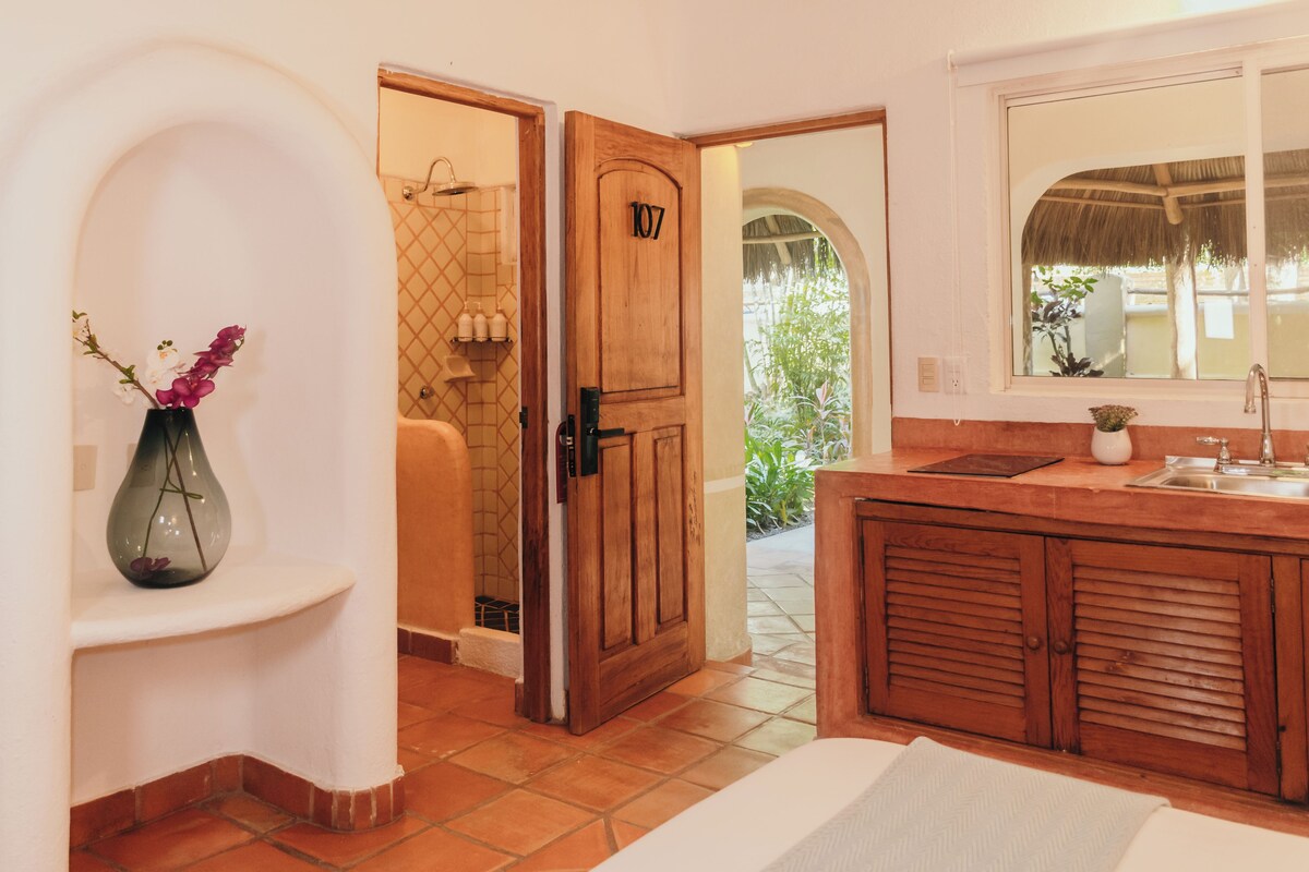 Casa de banho com porta de madeira, pia e janela com vista para o verde.