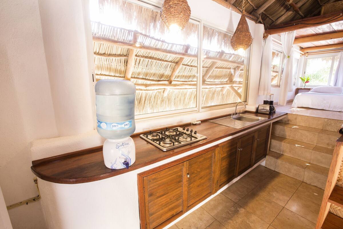 Une cuisine équipée d’un distributeur d’eau, d’une cuisinière et de meubles de rangement en bois.
