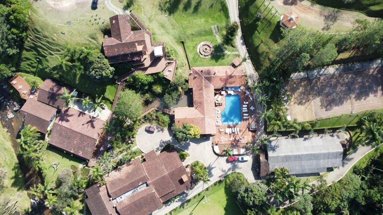 An aerial view of a residential area with multiple houses, a swimming pool, and a large building.