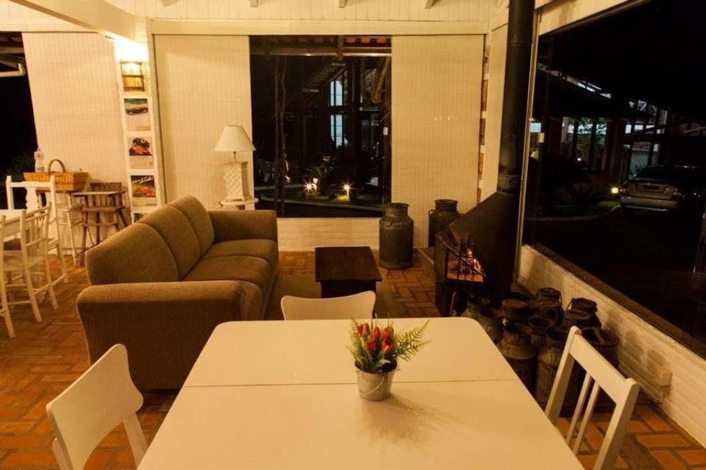Una sala acogedora con un sofá, una mesa de comedor con un florero y vistas al exterior de noche.