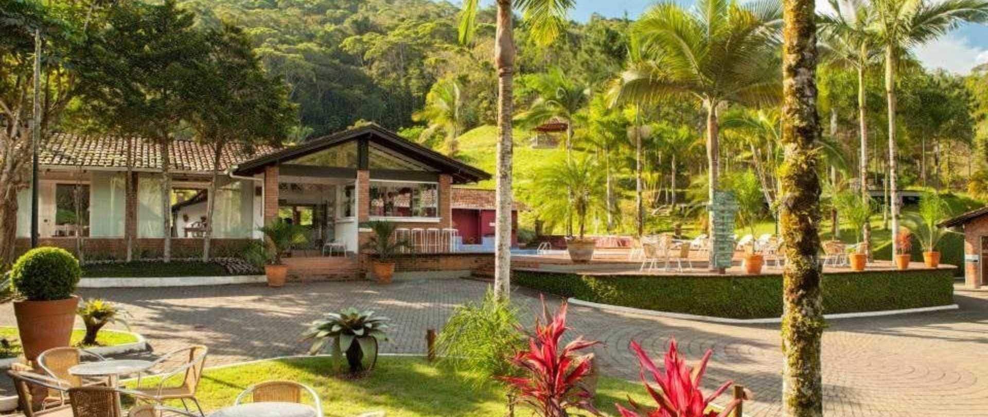 Een resort met een overdekte buitenzitplaats, een zwembad en weelderige begroeiing.