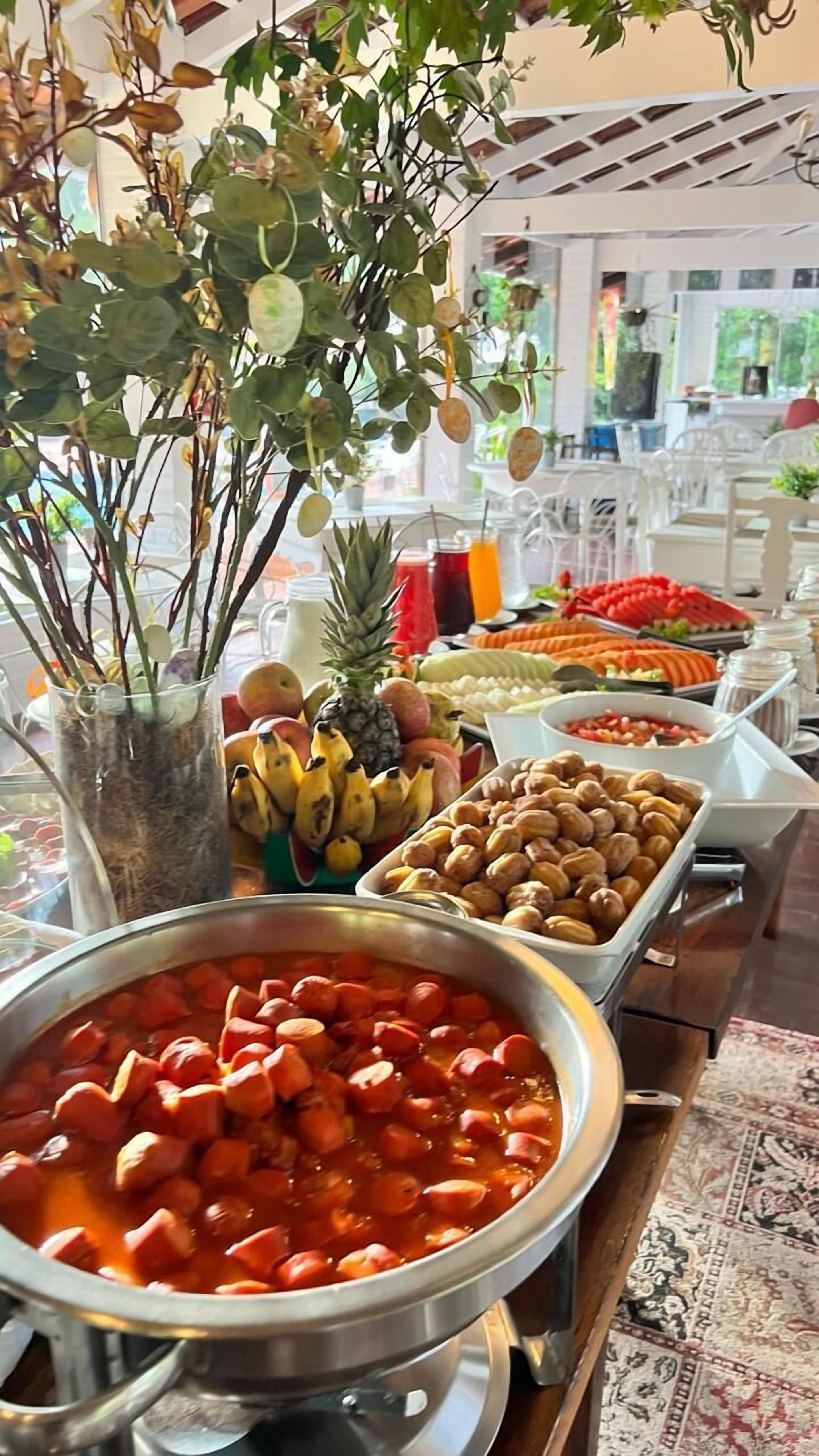 A buffet with various food items including fruits, nuts, and a pot of red stew.