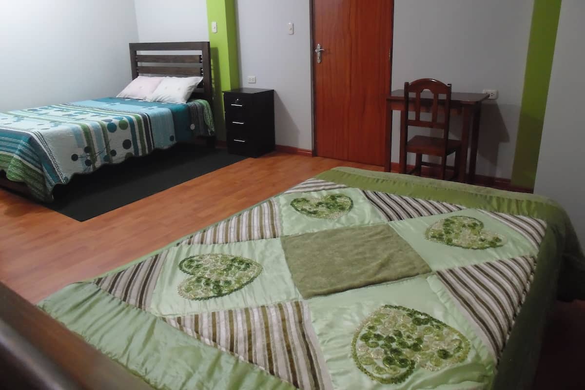 A bedroom with a bed, a desk, and a chair.