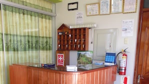 A reception desk with a wooden finish, a fire extinguisher, and a sign indicating a check-in time of 11:00 AM.