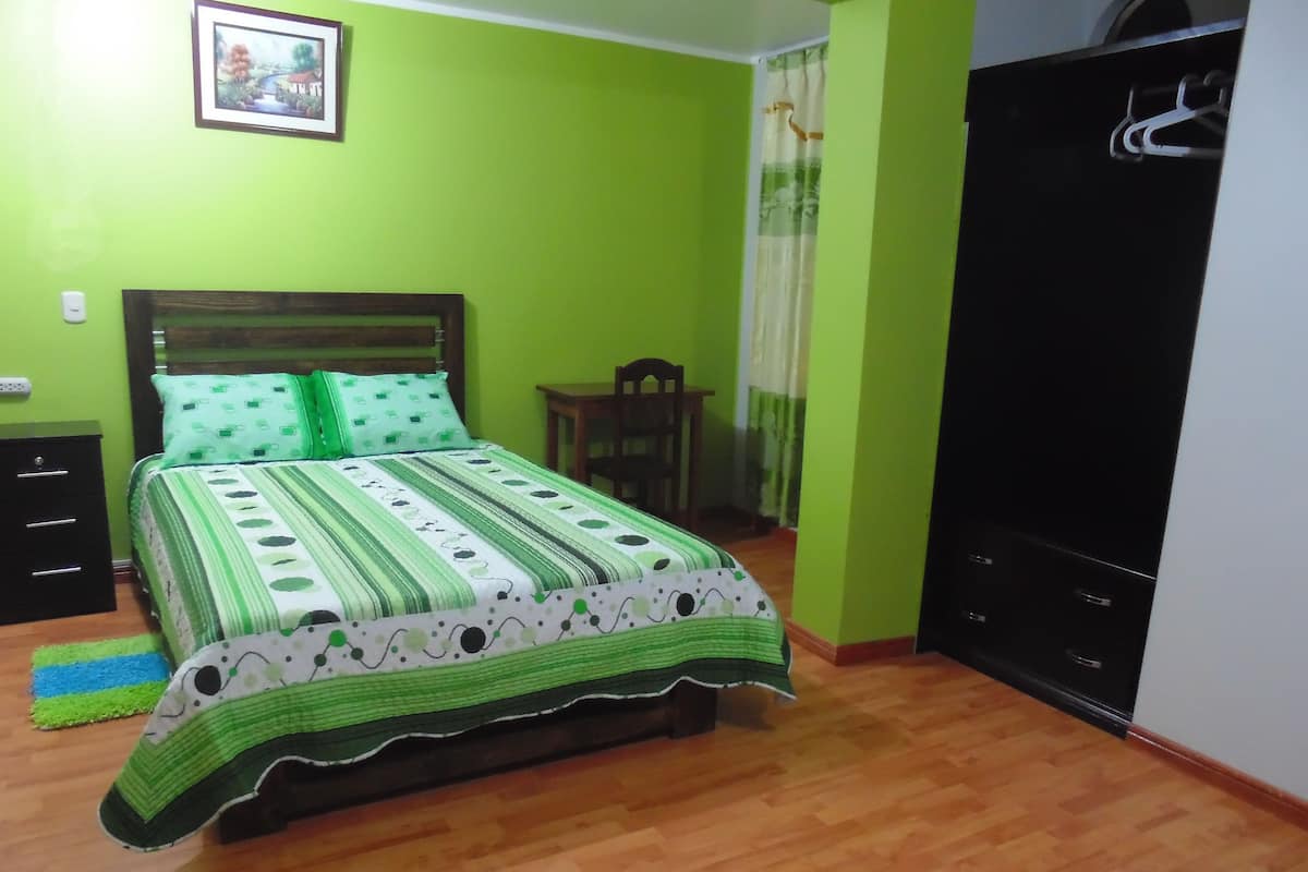 A bedroom with a bed, a dresser, a chair, and a wardrobe.