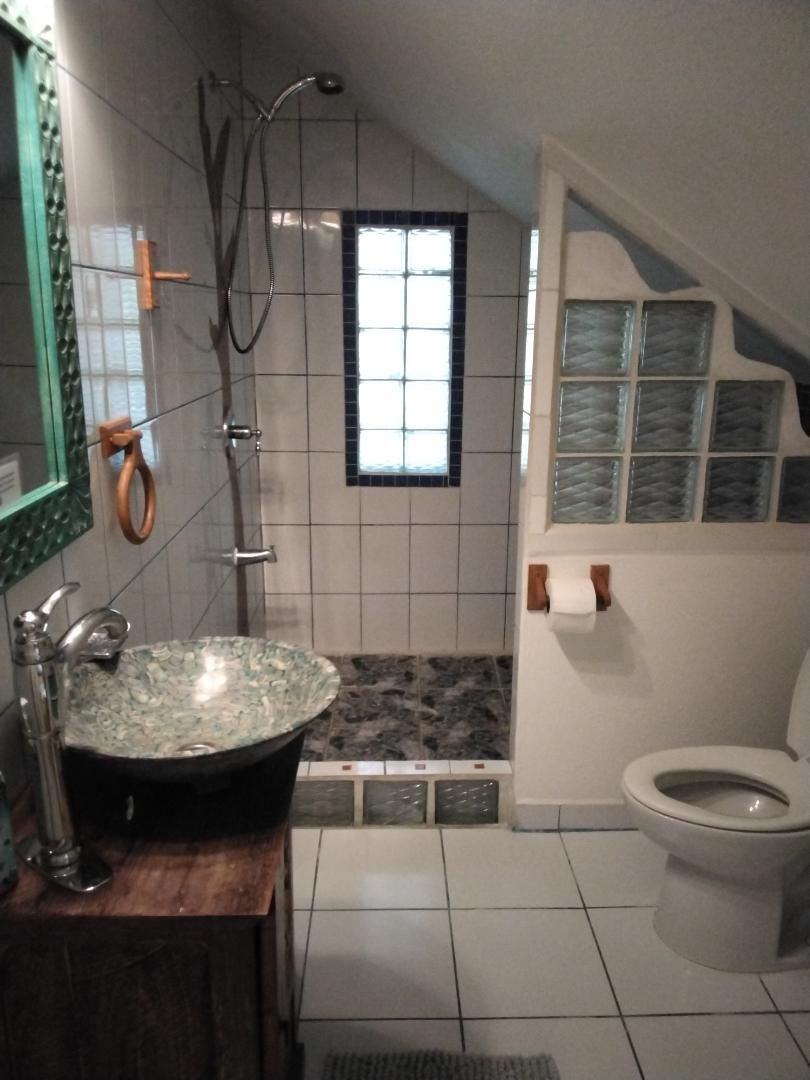 A bathroom with a freestanding sink, a shower, and a toilet.