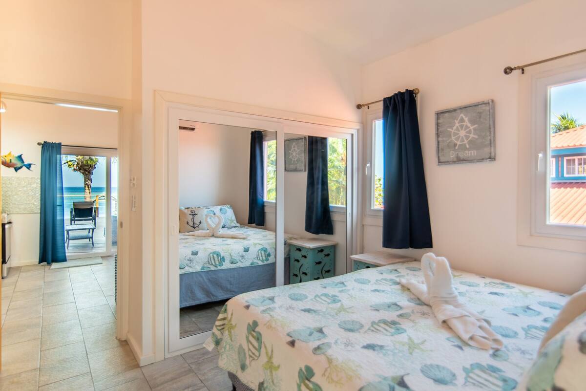 A bedroom with two beds, a view of the sea, and a balcony.