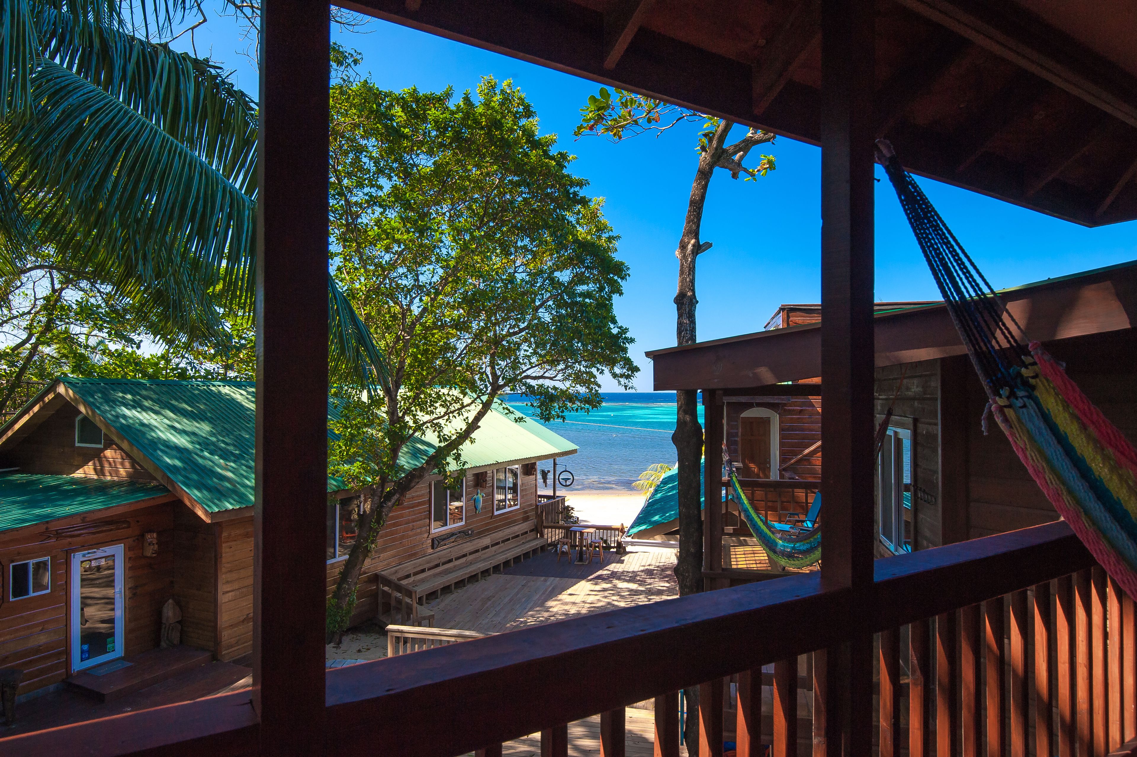 Una cabaña de madera con terraza que da a una playa y al océano.