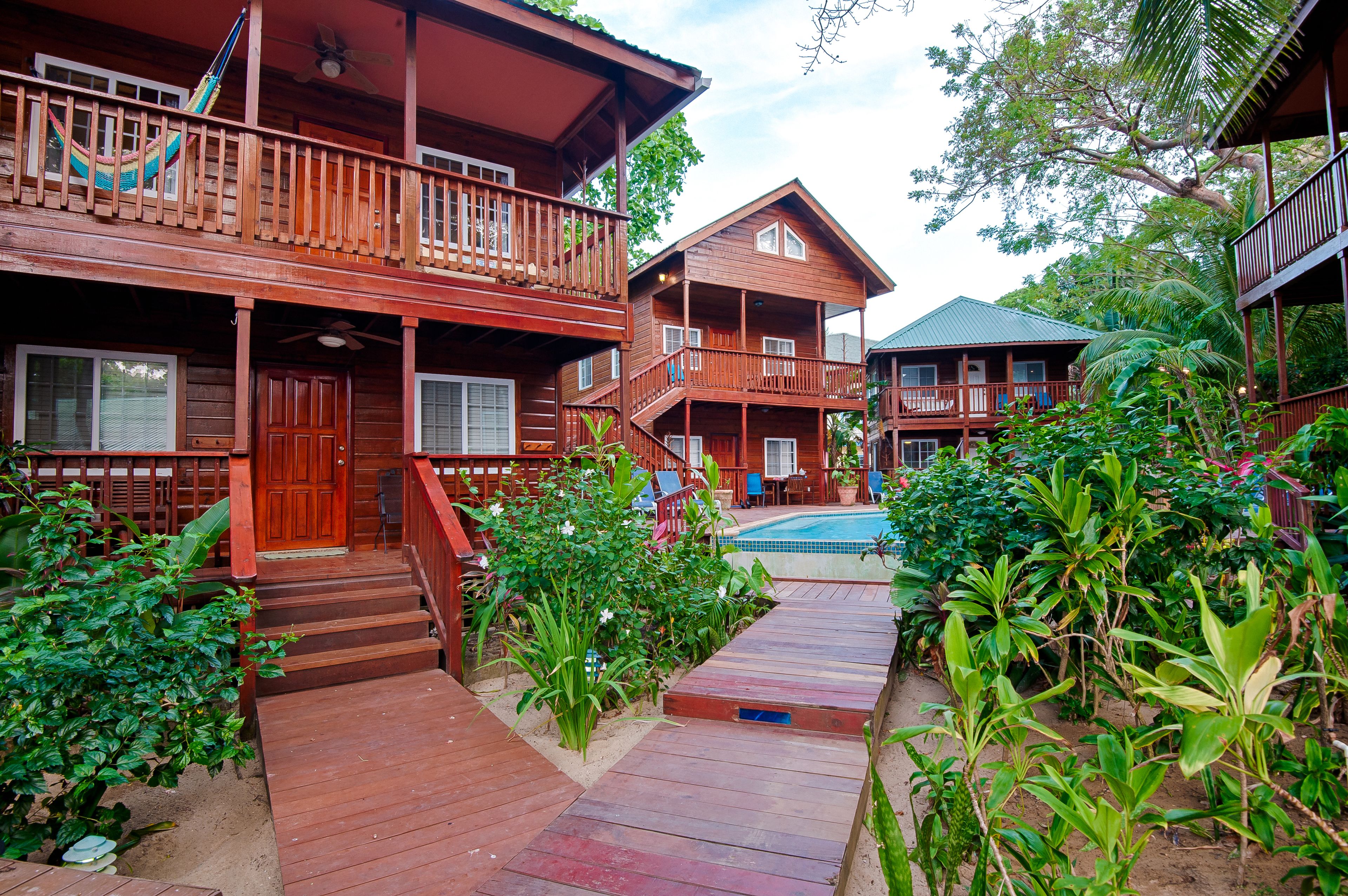 Una casa de madera con balcón, piscina y una escalera que conduce a la entrada.