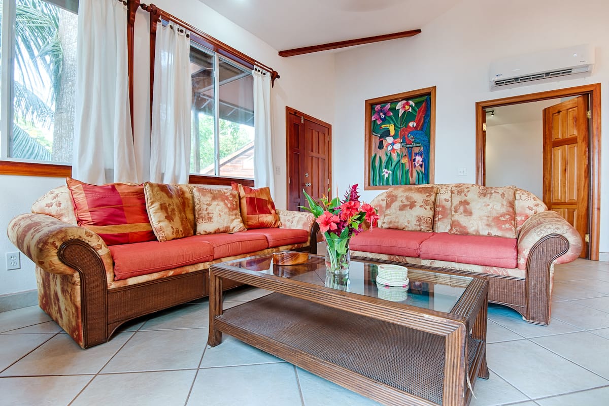 A living room with a sofa, a coffee table, and a painting on the wall.