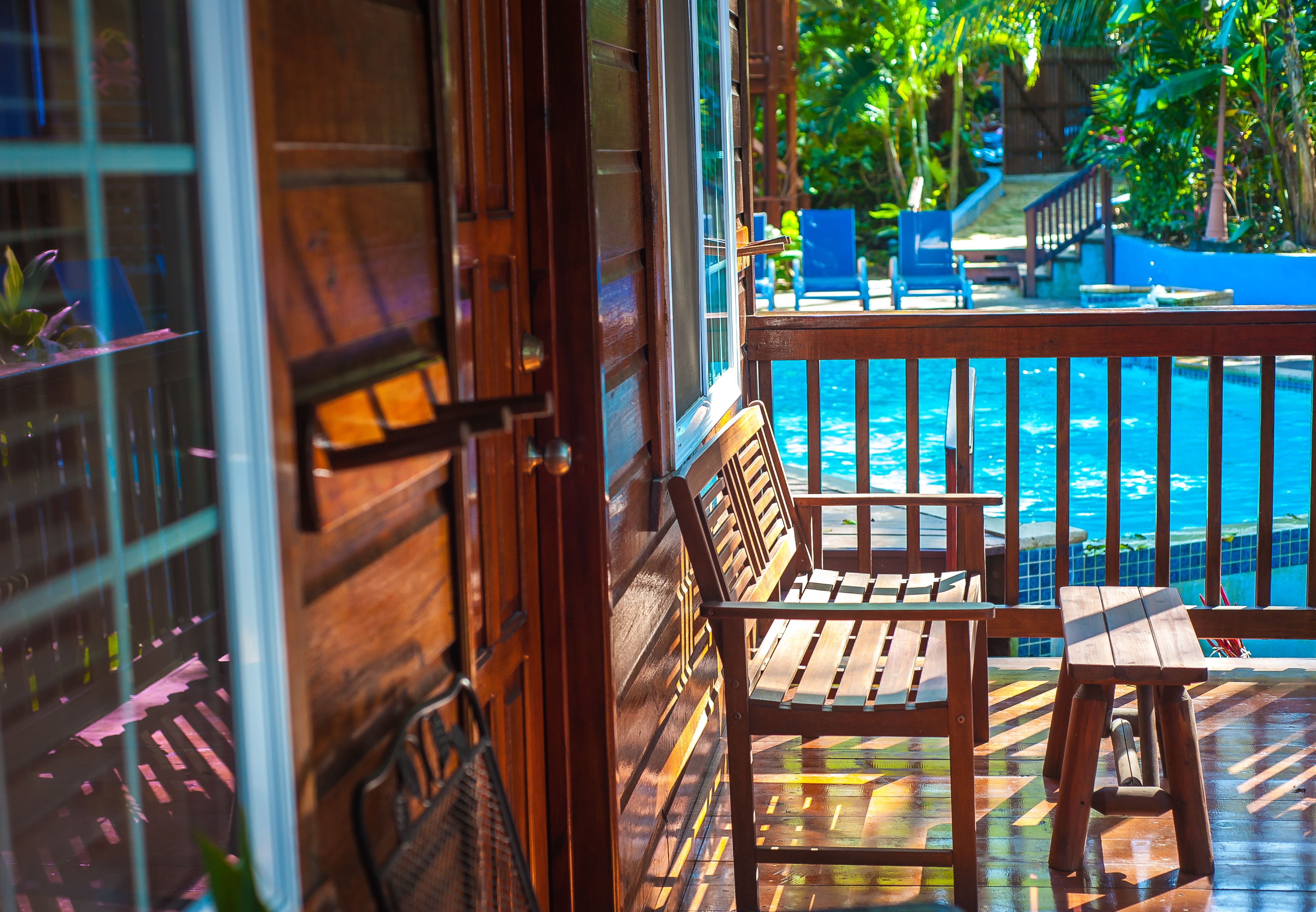 Una terraza de madera con piscina, sillas y una mesa.