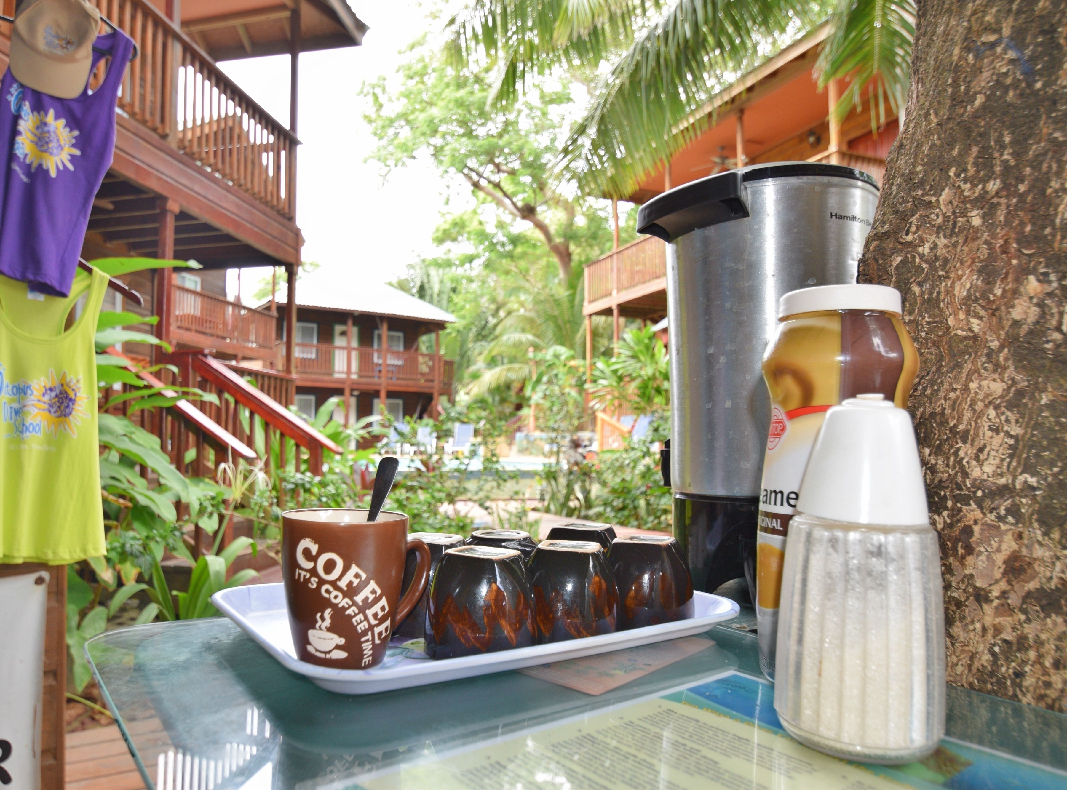 Une table avec un plateau à café, une tasse, un thermos et des condiments.