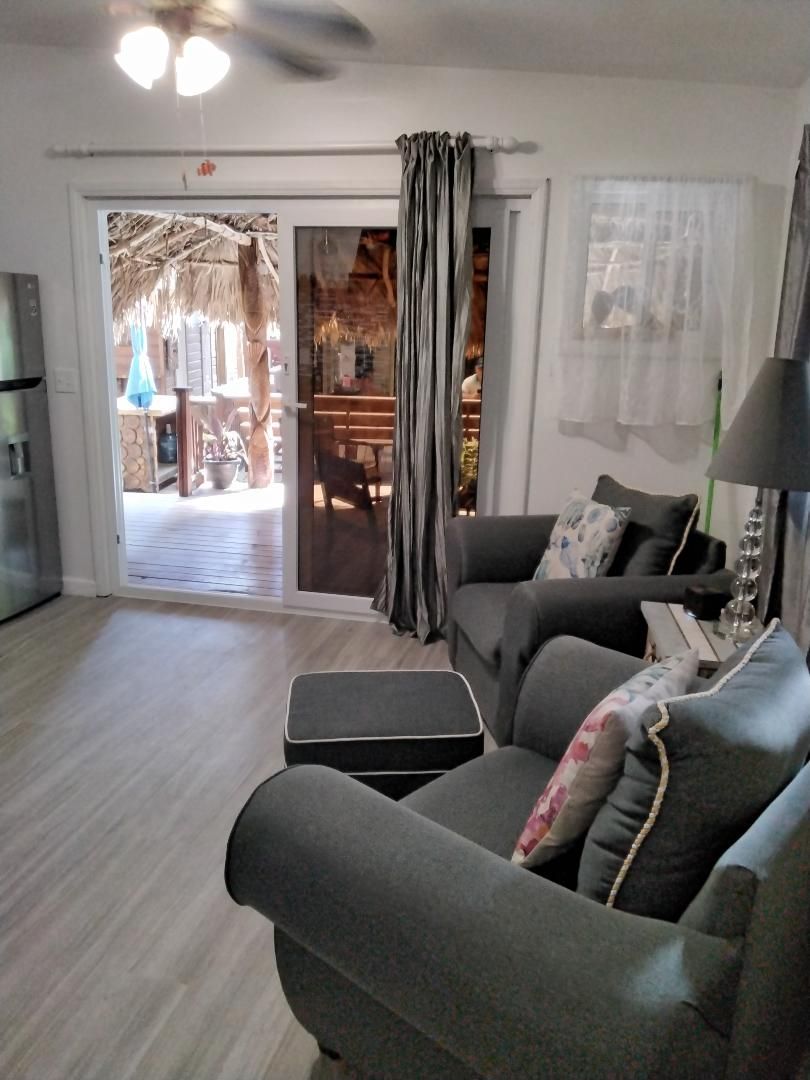 A living room with a sofa, a coffee table, and a lamp. There is a sliding glass door leading to an outdoor area.