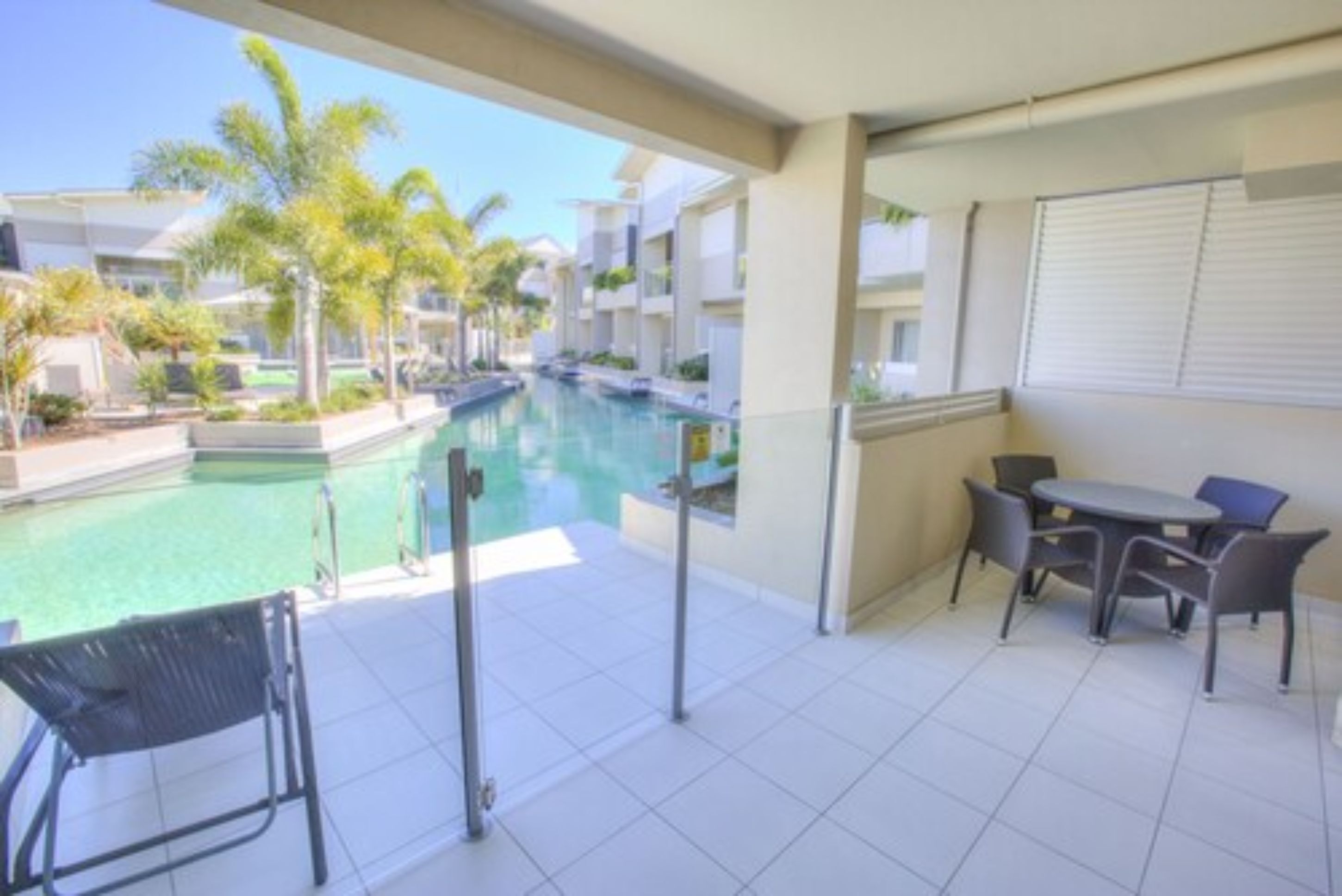 A balcony with a pool, outdoor furniture, and a view of other buildings.