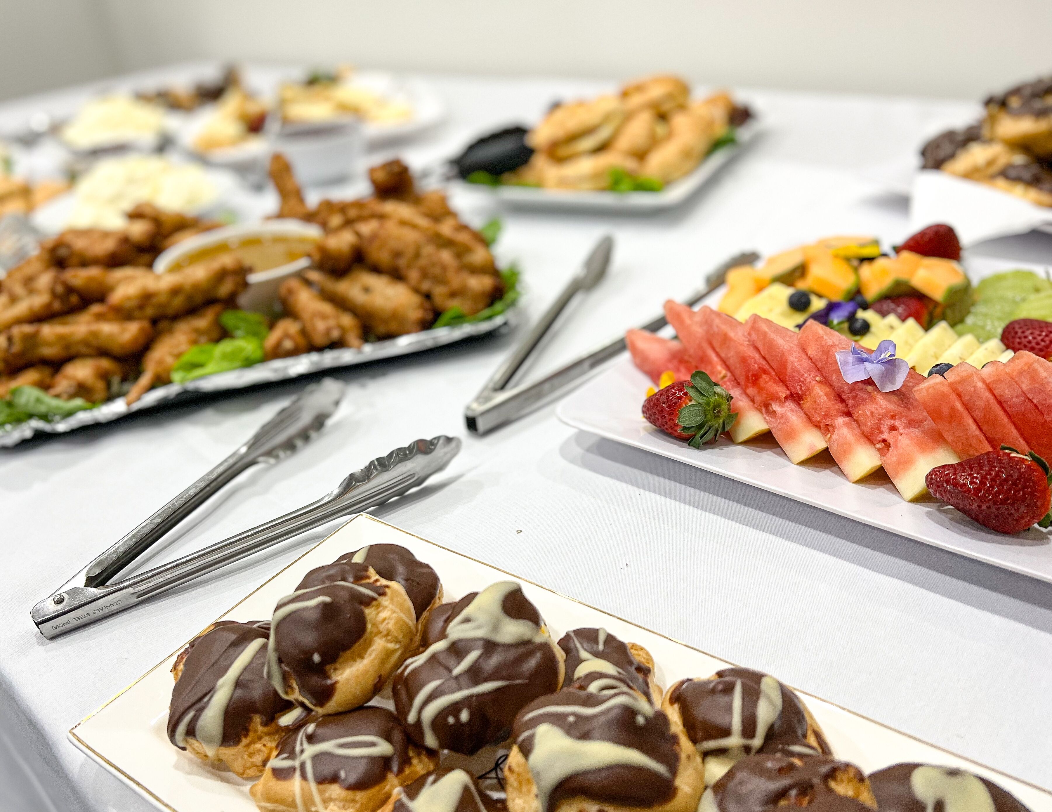 A buffet with various food items including fried chicken, fruit, and pastries.