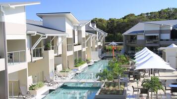 Un hotel de varios pisos con piscina, asientos exteriores y balcones.
