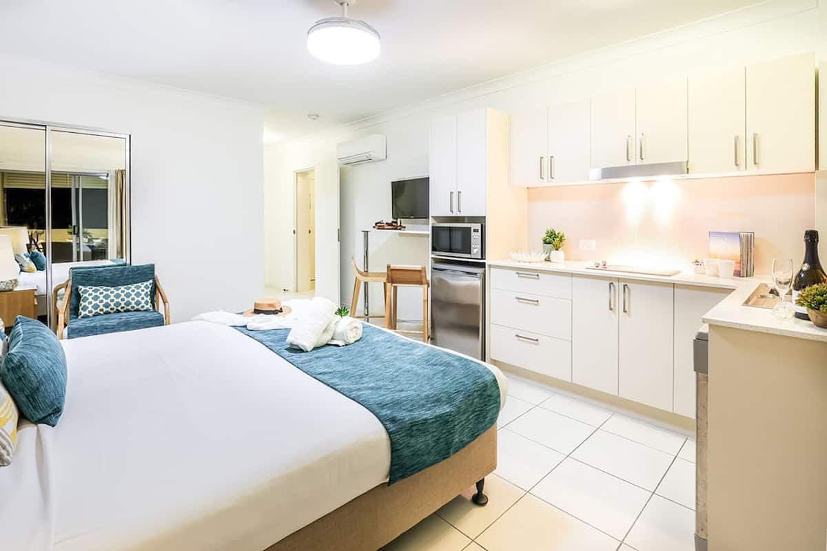 Een moderne hotelkamer met een groot bed, een kitchenette en een badkamer.