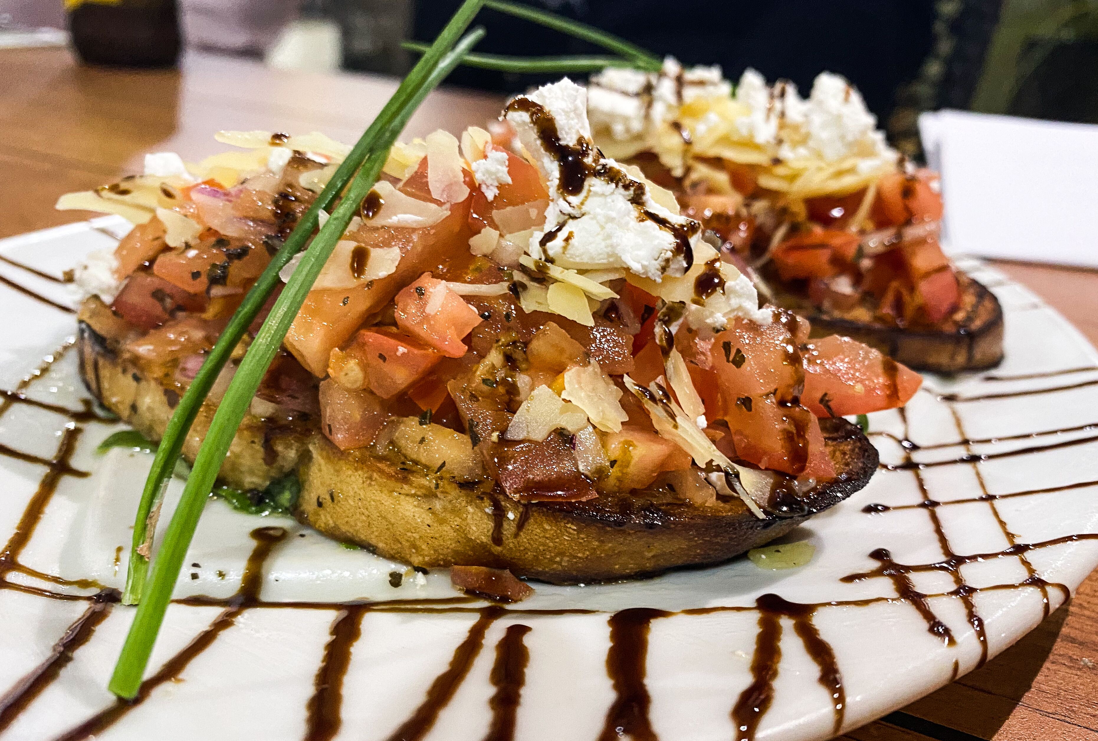 A plate of food with grilled vegetables and cheese, garnished with green herbs and drizzled with sauce.