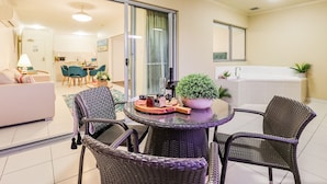Un salon moderne avec une porte vitrée donnant sur une cuisine, une table ronde avec des chaises, un canapé et une plante en pot.