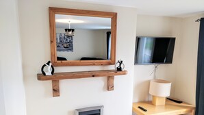 A living room with a fireplace, wooden shelves, a TV, and a lamp. - Millie and Charley's Apartments (Londonderry)