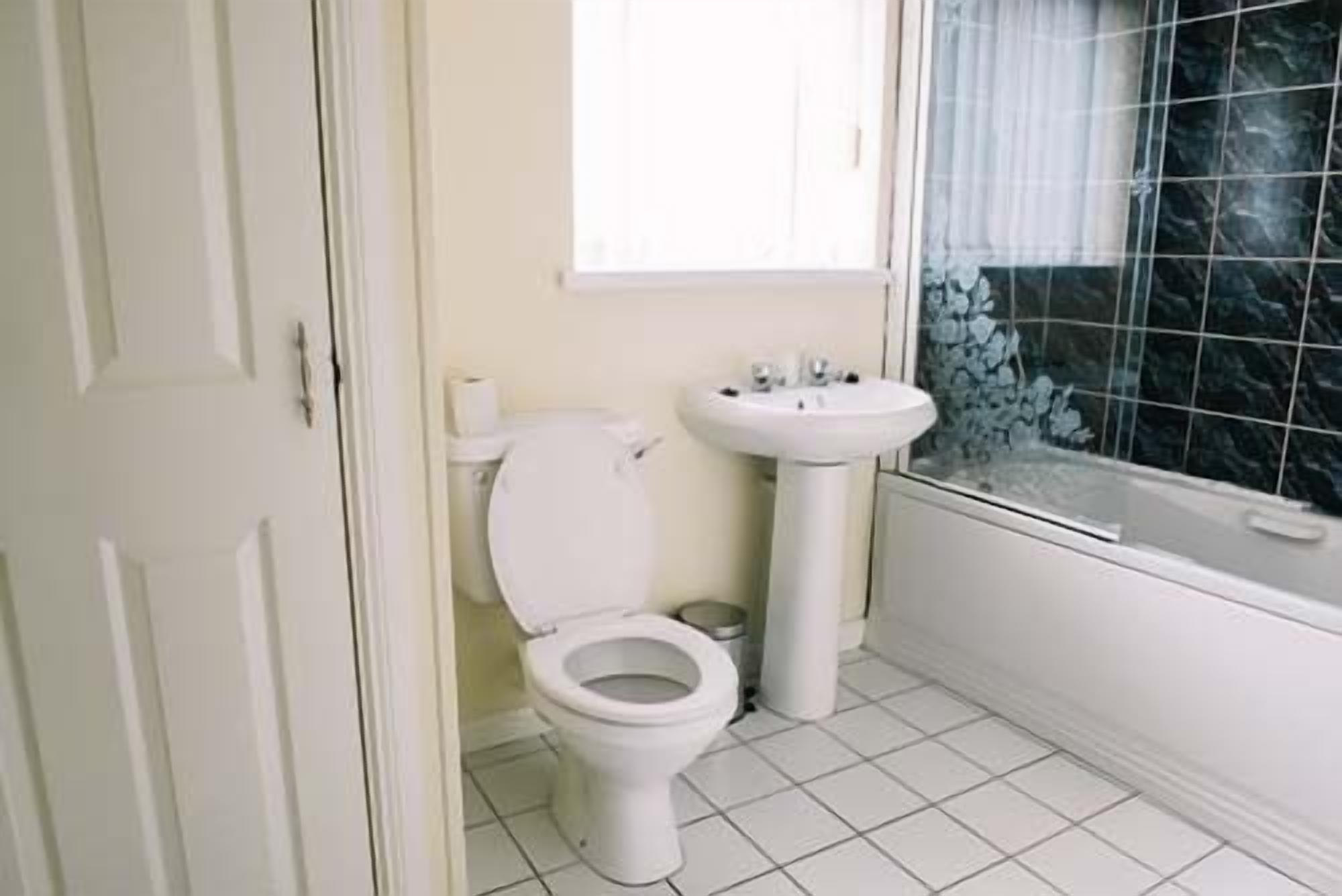 A small, clean bathroom with a toilet, sink, and bathtub.
