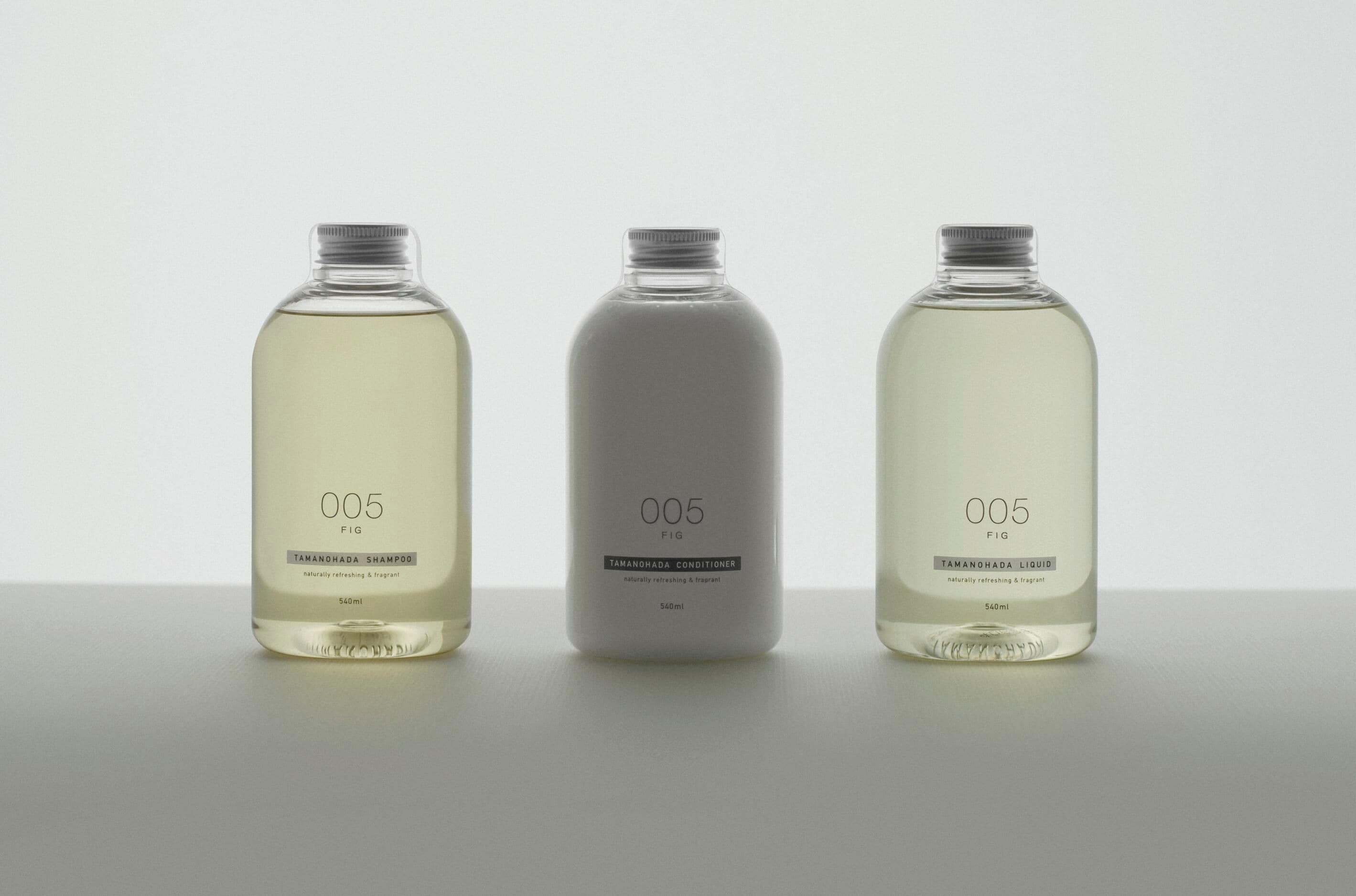 Tres botellas de un producto con la etiqueta '005 FIG' que contienen diferentes tipos de líquido.