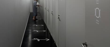 Un couloir avec des casiers et des flèches indicatrices peintes sur le sol.
