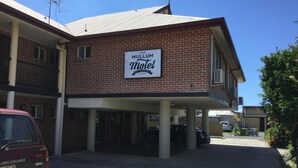 Een tweelaags bakstenen gebouw met een bordje met de tekst 'The Mullum Motel' op de gevel.
