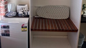 Een kleine kitchenette met een koelkast, broodrooster en waterkoker.