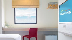 A hotel room with two beds, a red chair, a small white cabinet, a window with a view of the sky, and a 'Hop Inn' sign. - Hop Inn Phitsanulok (Phitsanulok)