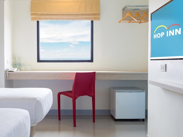 A hotel room with two beds, a red chair, a small white cabinet, a window with a view of the sky, and a 'Hop Inn' sign. - Hop Inn Phitsanulok (Phitsanulok)