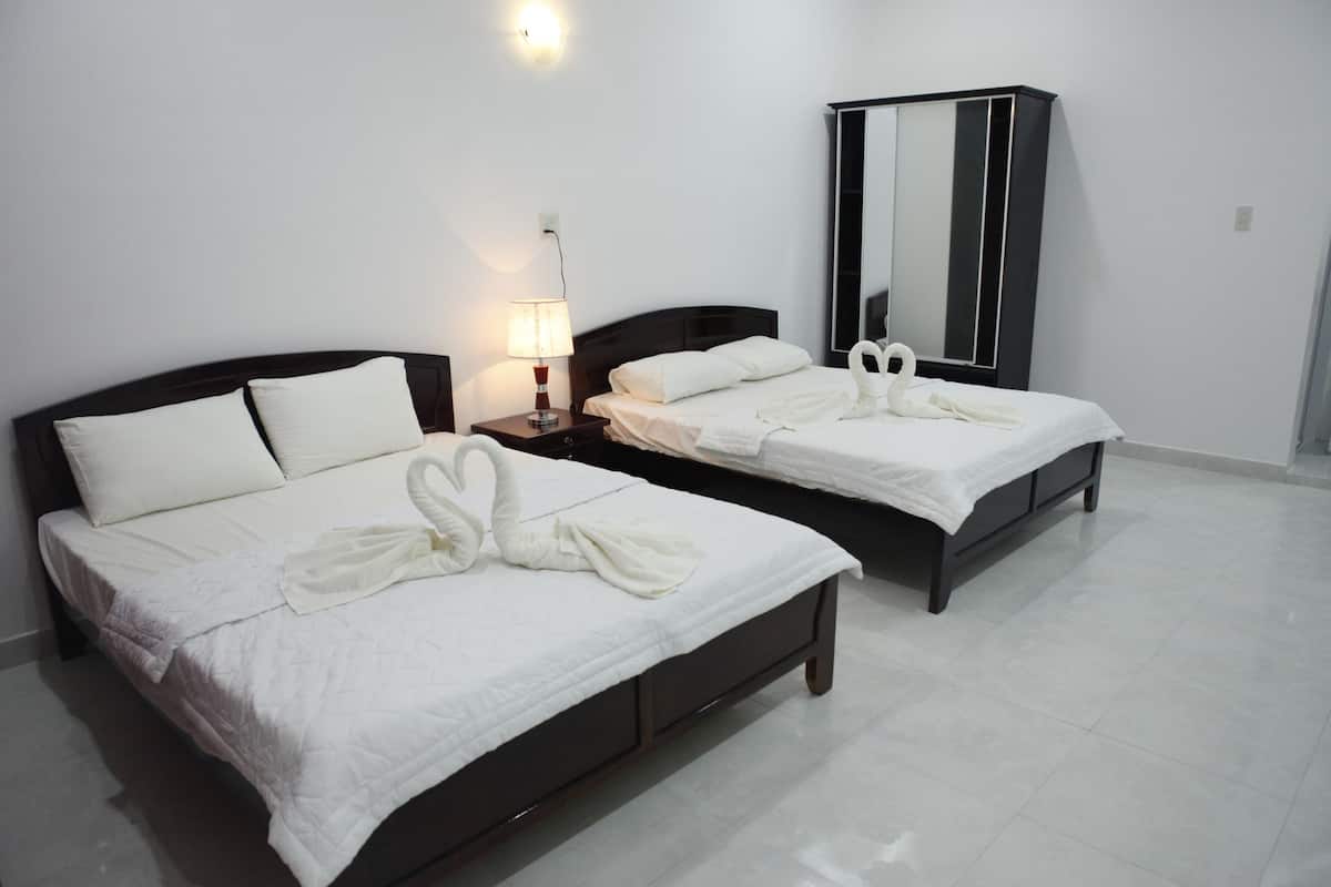 Two single beds with white bedding, a nightstand with a lamp, and a large mirror on the wall.