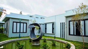 A modern building with a circular water feature in front. - Van Nguyen Minihouse (Mui Ne)