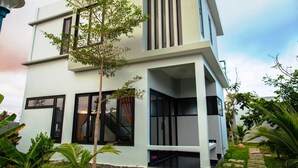 A modern two-story building with large windows and a staircase leading to the upper floor. - Van Nguyen Minihouse (Mui Ne)