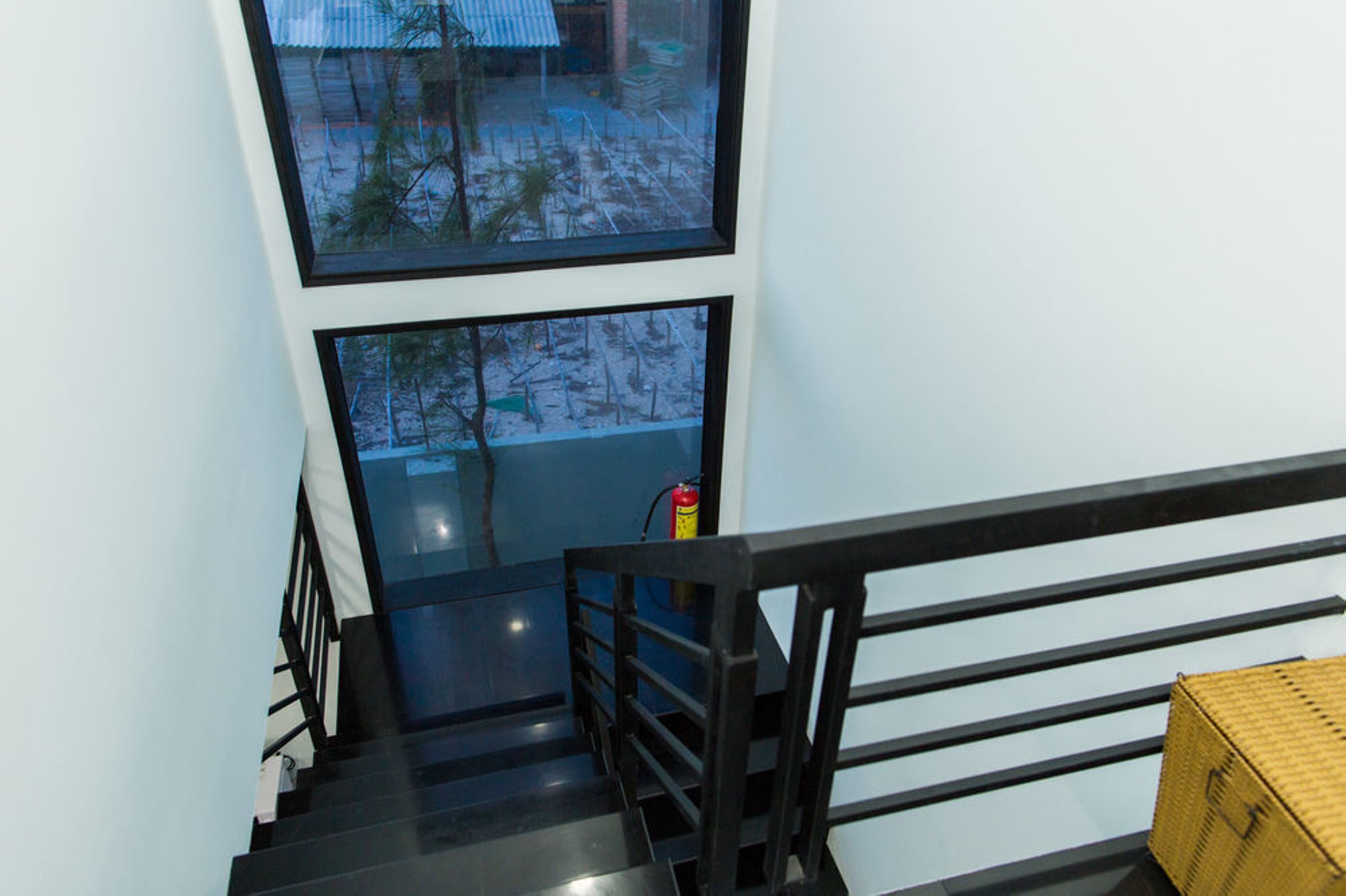 A staircase with black railings and a fire extinguisher on the wall.